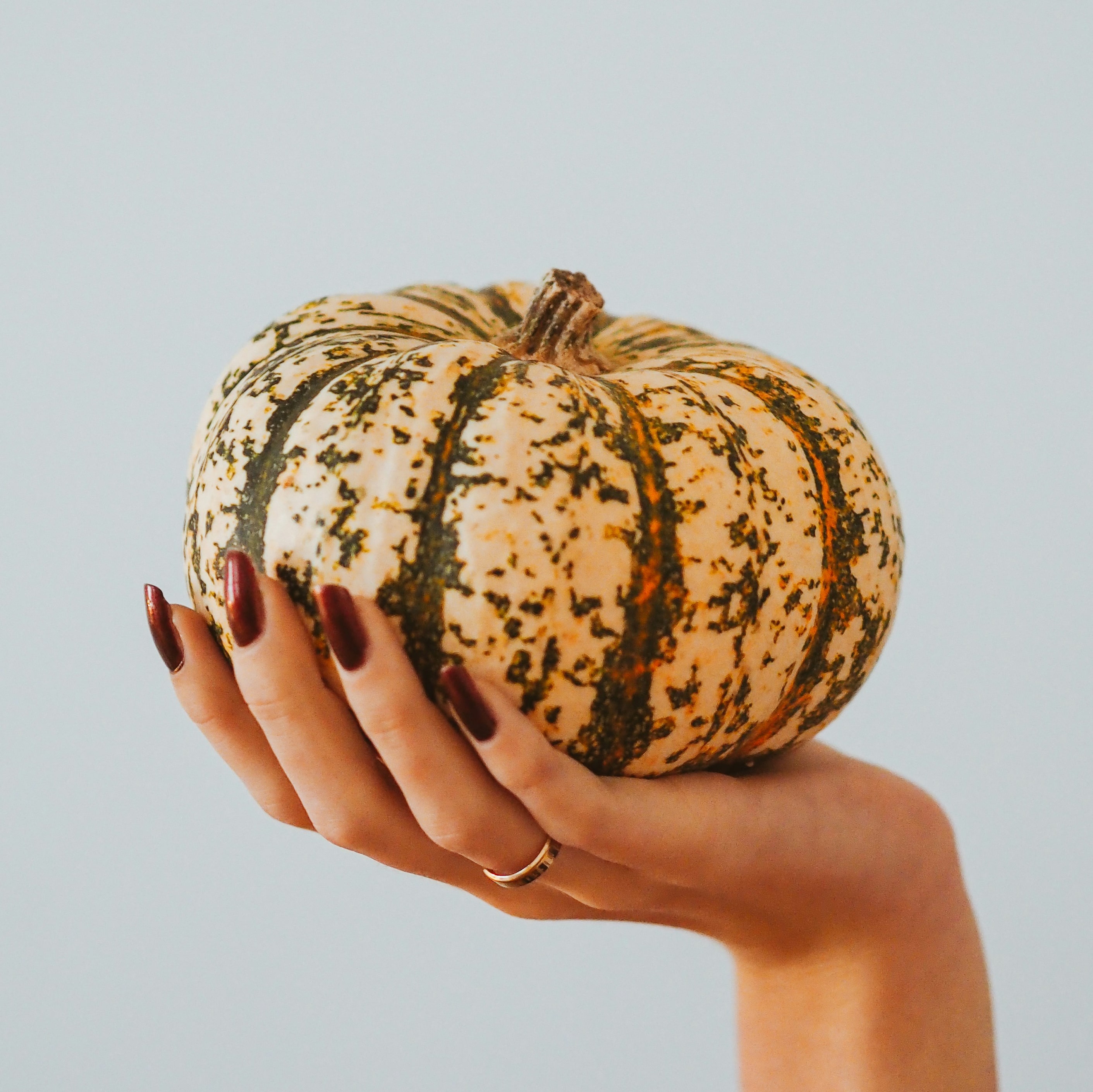 An orange acorn squash in the palm of a person